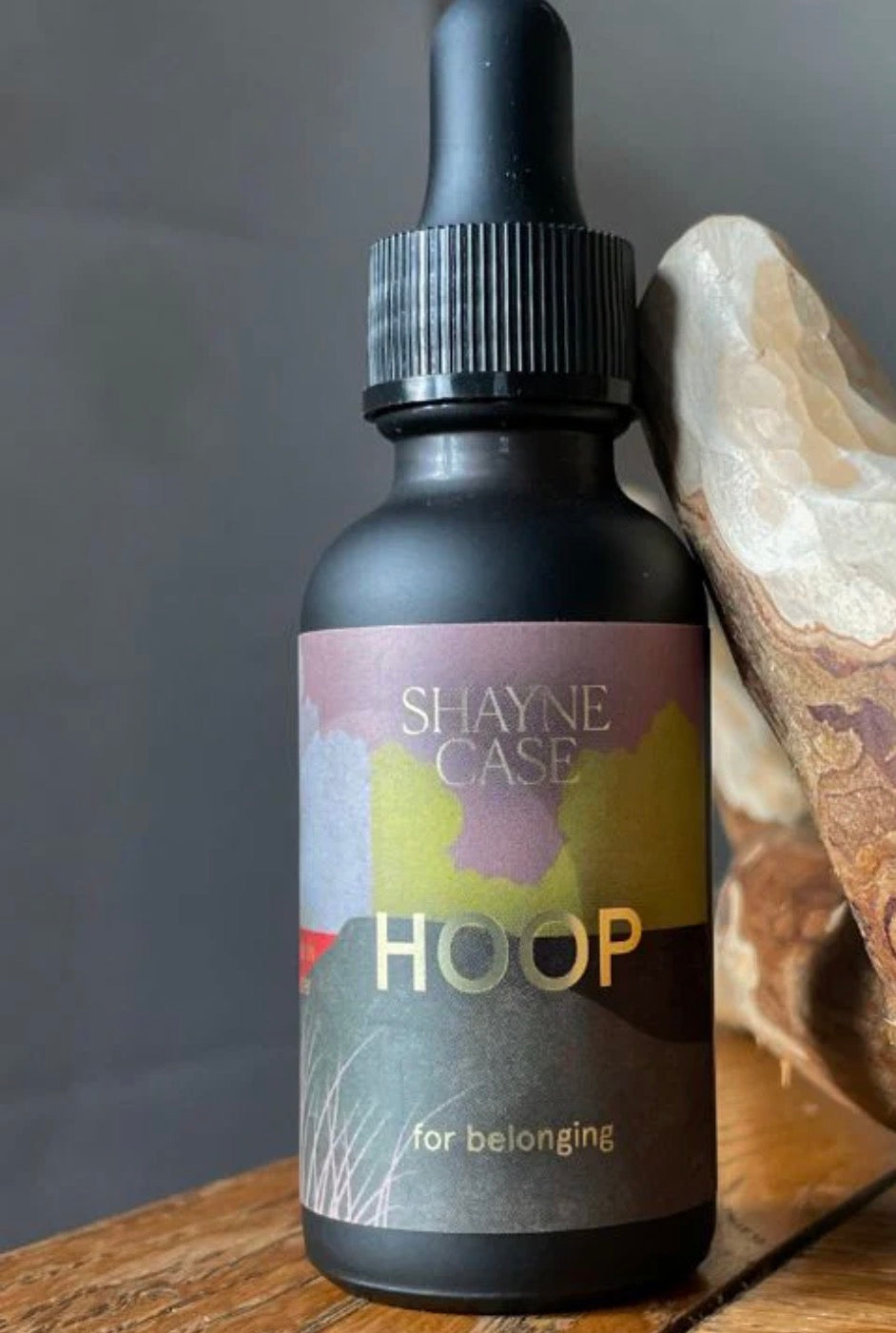 Bottle labeled 'Shayne Case Hoop' on a wooden surface with a blurred background