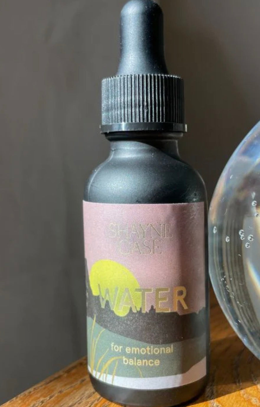 Bottle labeled 'Water for emotional balance' with a dropper on a wooden surface.