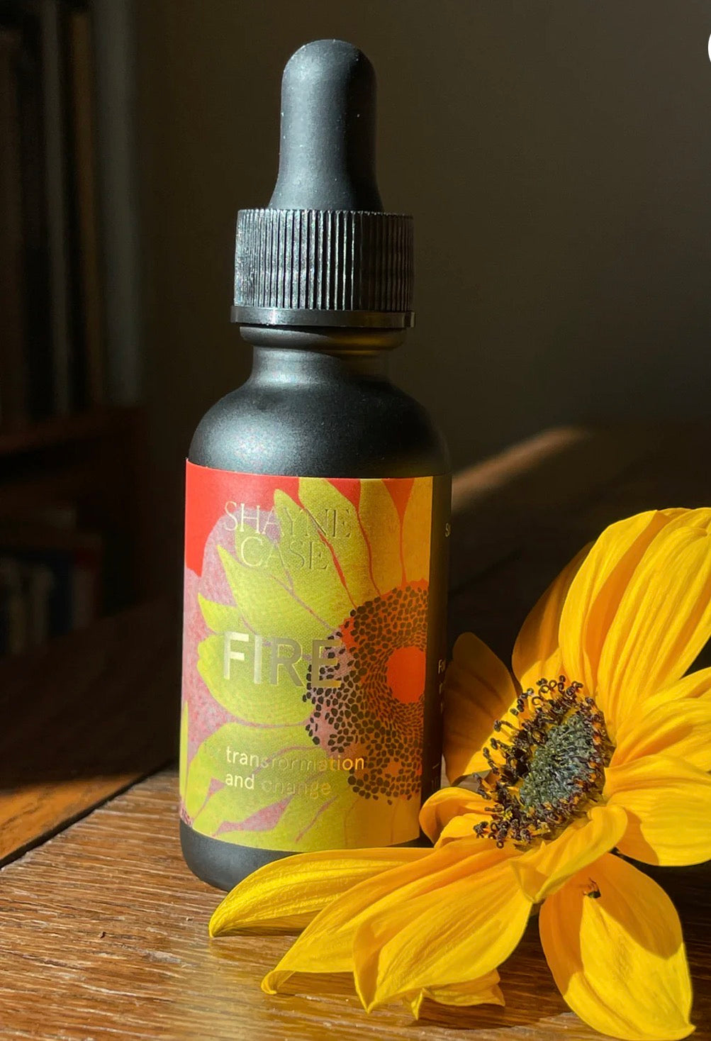 Bottle labeled 'Fire' with a sunflower on a wooden surface